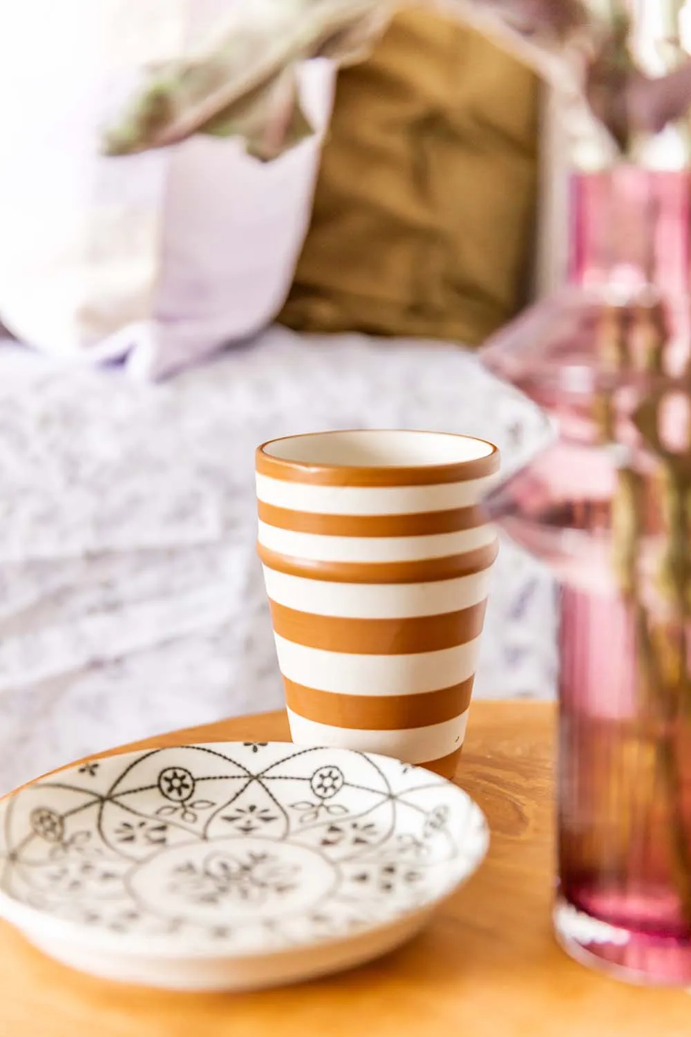 Striped ceramic cup and patterned saucer on a bedside table