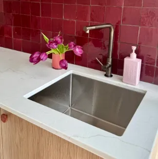Stainless steel sink against burgundy tiles with pink tulips