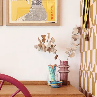 Sideboard vignette with dried stems in a pink vase and a yellow artwork
