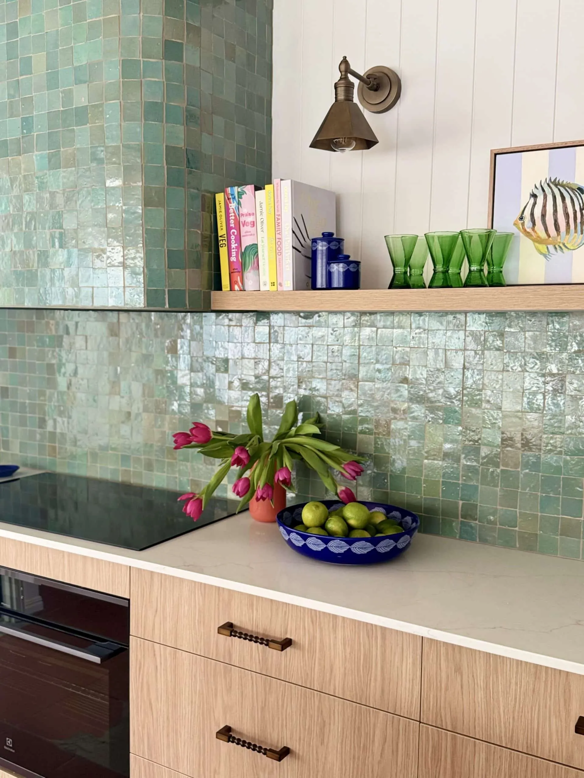 Green zellige tile splashback with tulips and a blue fruit bowl on the bench