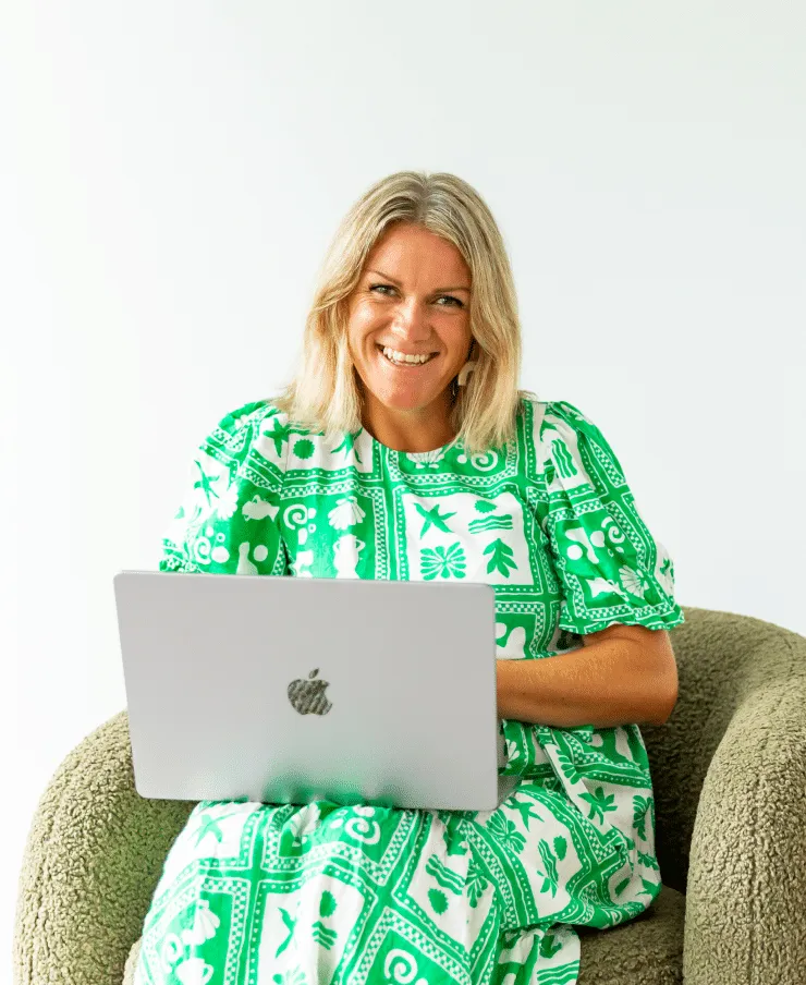 Sara Cornish, interior designer at YUZU Interiors, working on a laptop in a green patterned dress